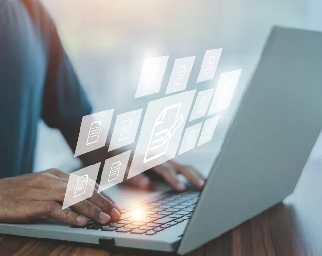 A close-up of a person's hands typing on a laptop, with a bright, warm glow emanating from the keyboard. Floating above the laptop is a transparent digital interface displaying a workflow of glowing document icons.